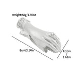A large antique silver metal clamp shaped like a detailed hand holding large rose bouquets (no pearl detail). A visible rhinestone ring is on the finger. Ideal for taming stubborn pages in thick junk journals and gothic book accessories.
