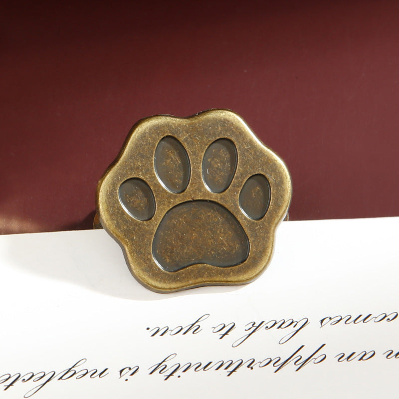 Antique bronze cat paw metal clip with vintage patina finish on dark red background