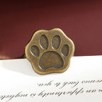 Antique bronze cat paw metal clip with vintage patina finish on dark red background