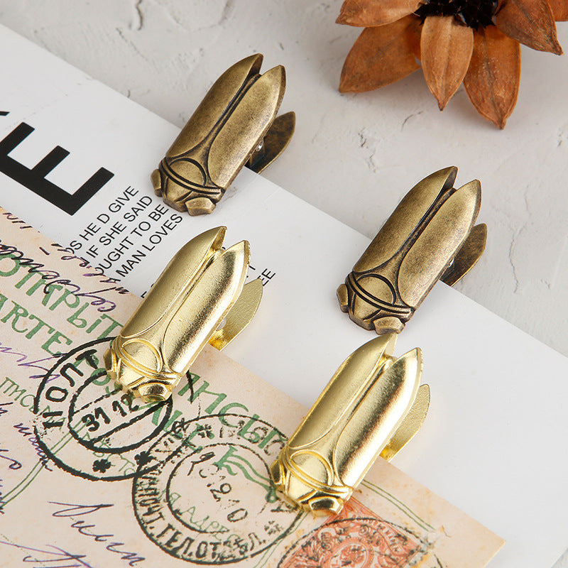 A grid collage displaying four views of the cicada metal journal clip, including Aged Antique Bronze and Luminous Gold variations. Images show the intricate details, the clip held by hand, and the heavy-duty spring mechanism clamping a stack of aged paper.