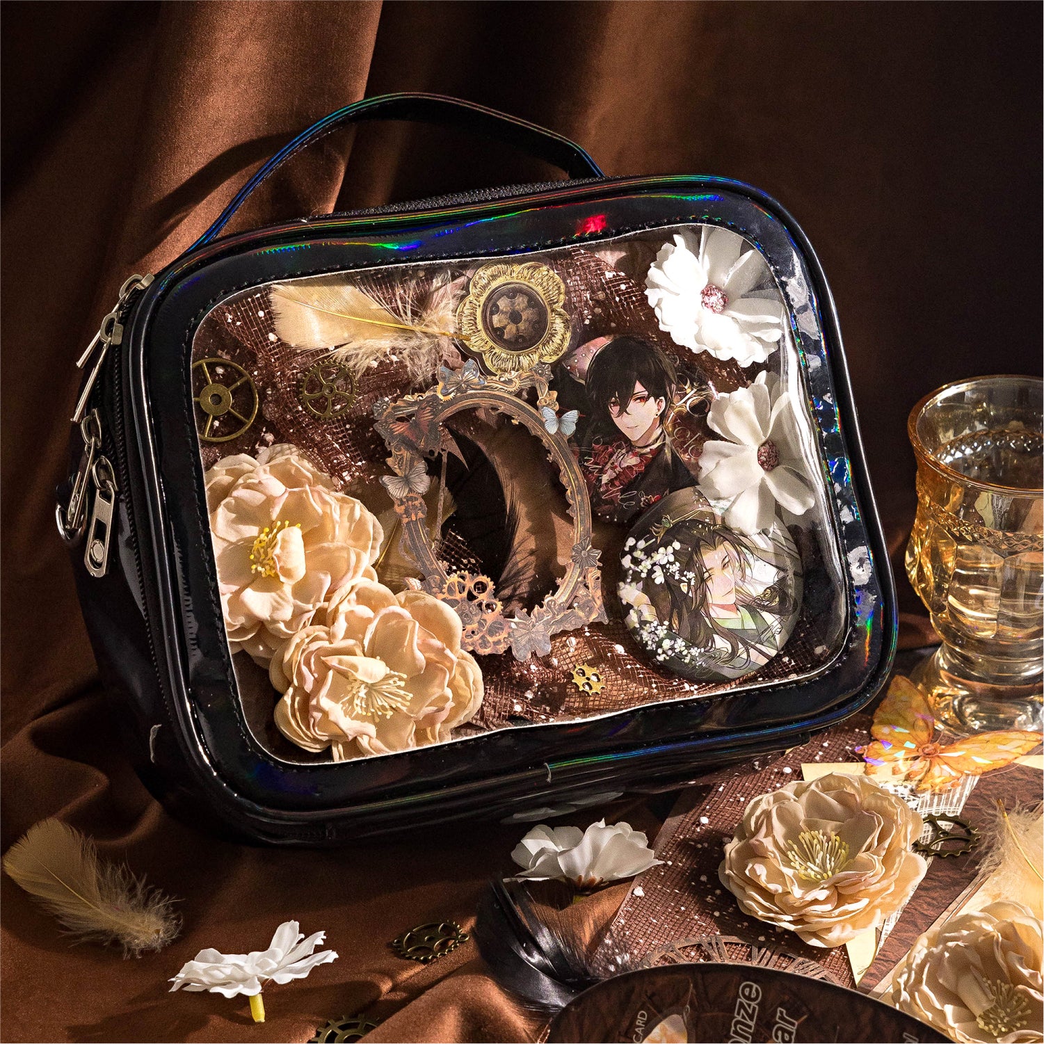 Steampunk aesthetic Ita bag decoration using the Clockwork Bronze mixed media kit. The insert features anime character pins arranged with vintage laser-cut frames, brass gears, beige 3D flowers, and dark feathers.