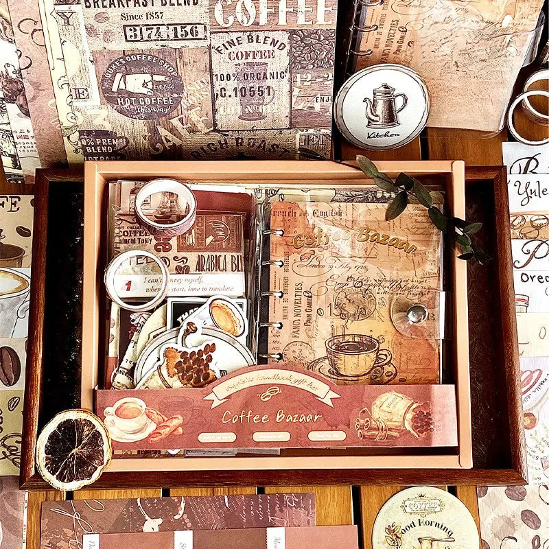 The Coffee Bazaar vintage aesthetic journal gift box opened on a wooden desk. Inside is a transparent A6 binder notebook, washi tapes, and coffee ephemera perfect for Dark Academia planners.