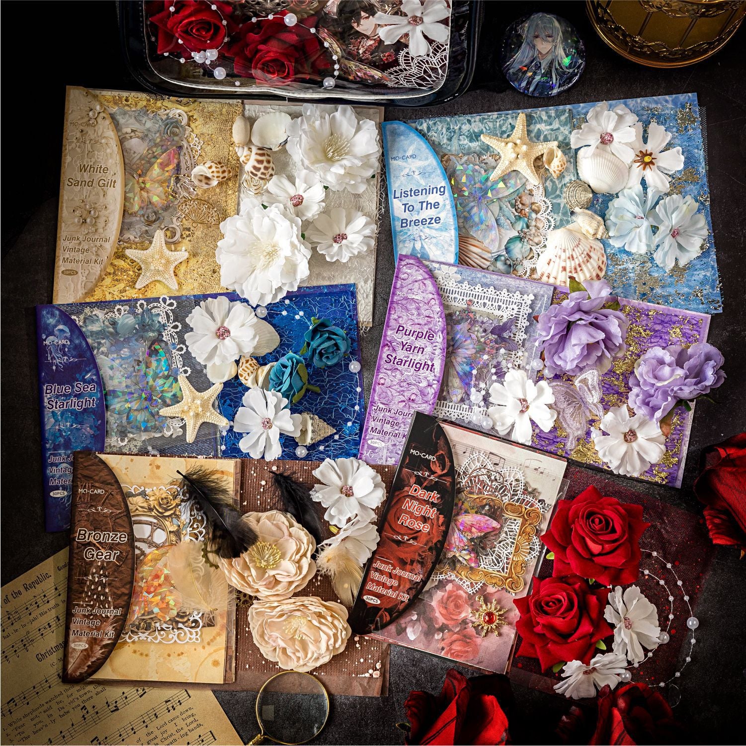 Overhead view of all six styles of the Premium Mixed Media Junk Journal Kit collection, including Midnight Rose, Celestial Ocean, and Clockwork Bronze. Each pack displays its unique color palette, 3D flowers, and holographic elements.