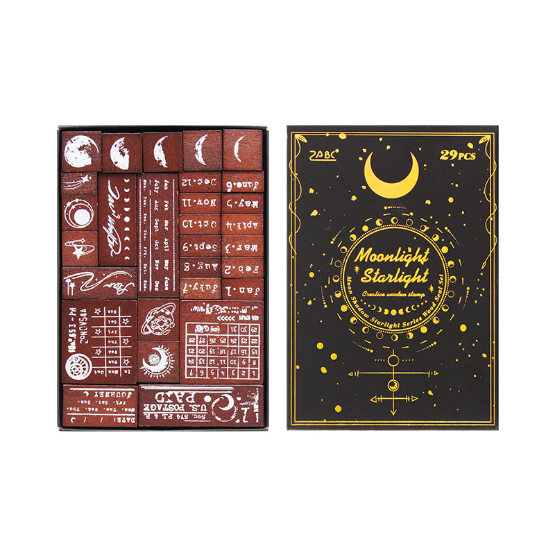 Clean studio shot of the complete Moonlight Starlight vintage wooden stamp set on a white background. Shows the luxurious black and gold-foil cover next to the 29 intricately designed celestial and postal stamps.