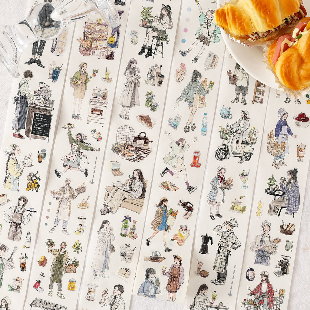 Opened box of the 'Cozy Café' washi tape set on a wooden table, next to a ceramic cup. The 6 rolls feature aesthetic illustrations of girls with coffee, fresh bread, and relaxing everyday life.