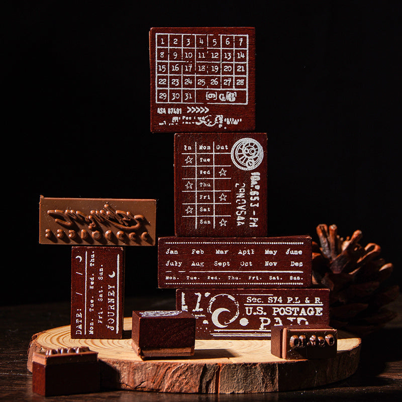 A creative stack of the Moonlight Starlight wooden stamps resting on a wood slice, highlighting the deep-etched red rubber bases and intricate calendar and postmark designs designed for crisp ink impressions.