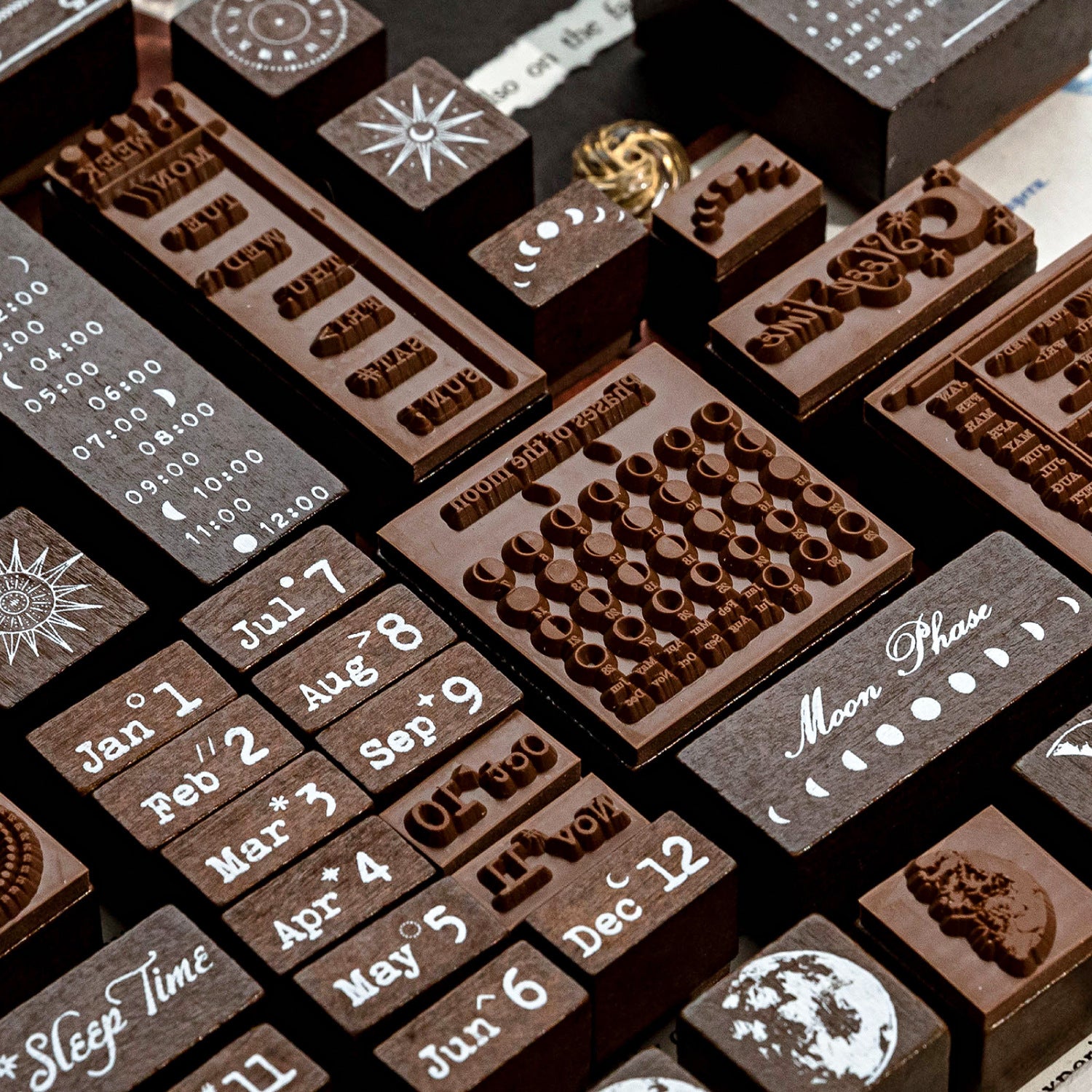 Macro close-up of the deep-etched rubber bases on the celestial wooden stamps. Shows the intricate details of the moon phases, mini calendars, and sunbursts, designed for flawless and crisp ink impressions.