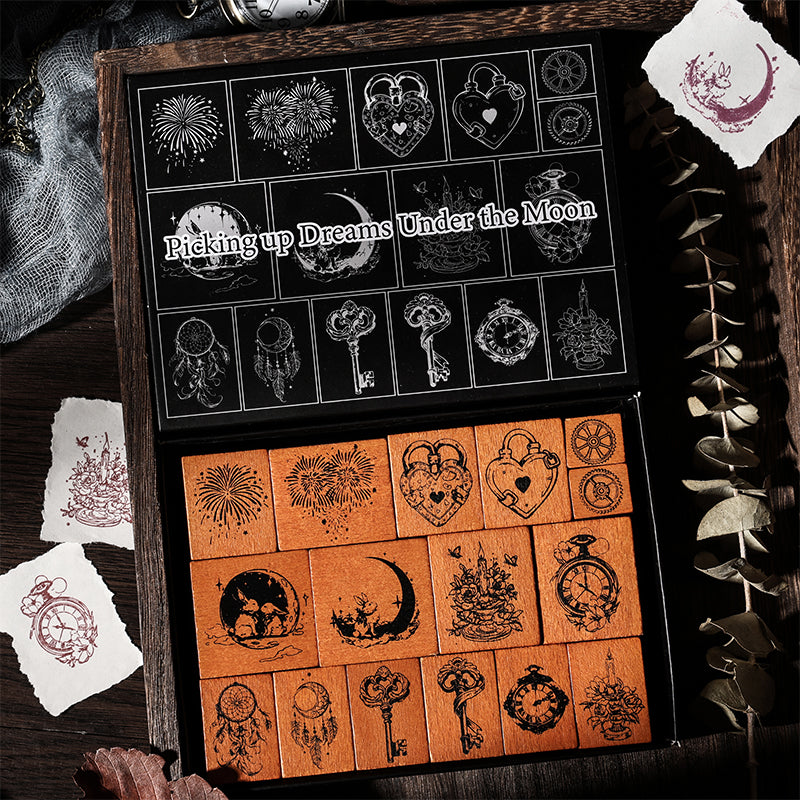 The Dreams Under the Moon 16-piece solid wooden stamp set displayed in its black aesthetic box. Features mystical rabbit, vintage pocket watch, and dreamcatcher designs for junk journaling.