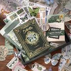 Comprehensive flat lay showcasing the 140-piece Emerald Forest botanical green journaling kit. The collection features a butterfly cover A6 notebook, green memo papers, gold clips, vintage ephemera, and PET butterfly stickers for Cottagecore crafting.