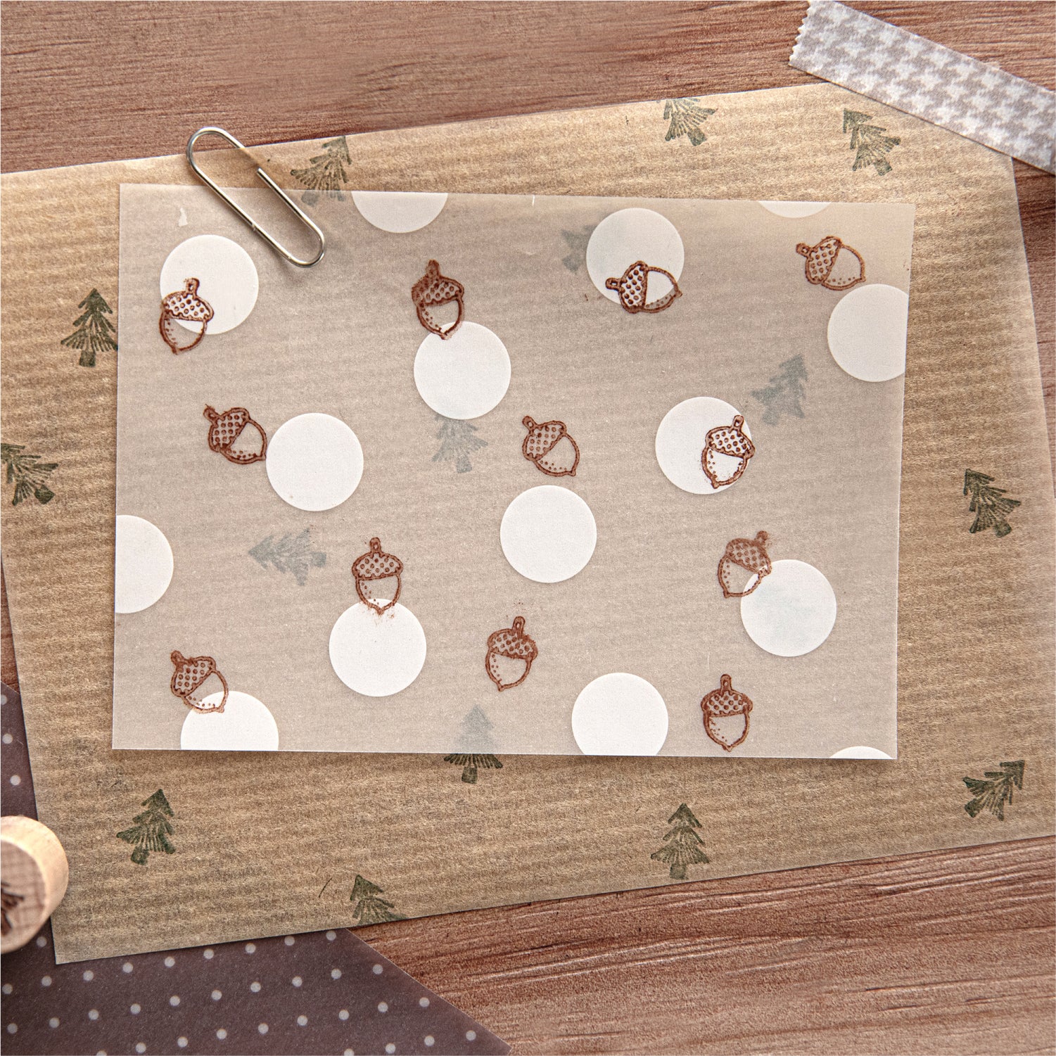 Pinecone and pine tree rubber stamp impressions on kraft paper with white circle labels, brown ink.