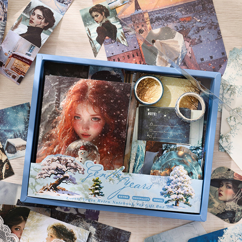 A hand gently opening the Gentle Years grey-blue aesthetic journal kit gift box, perfect for winter fairytale themed scrapbooking.