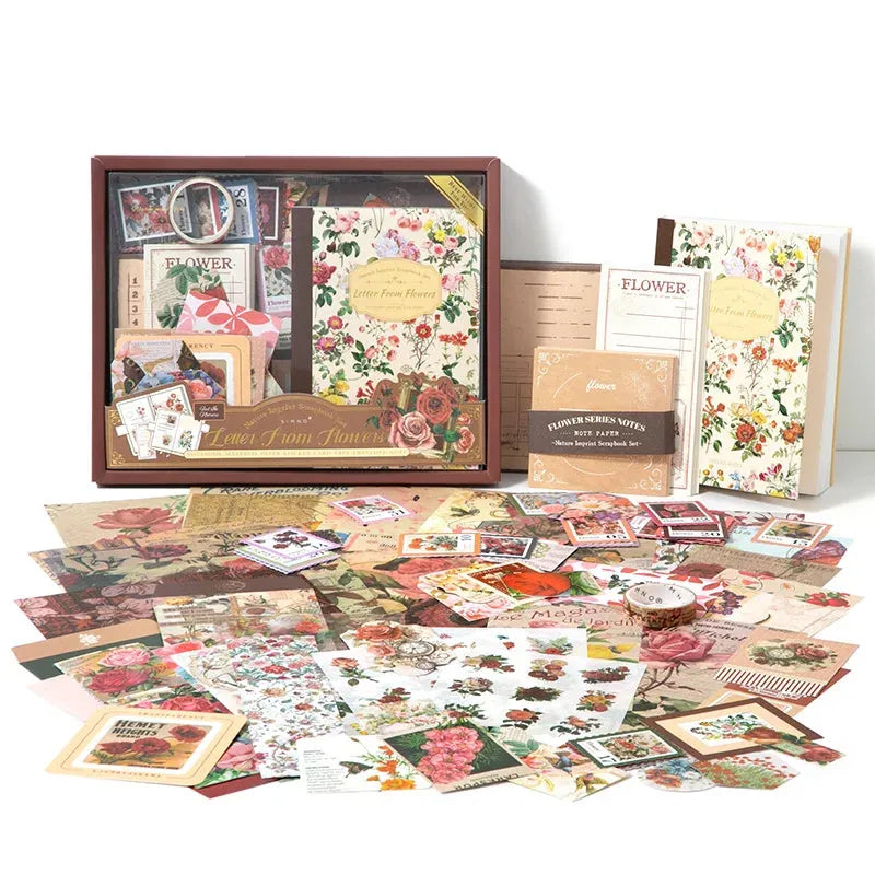 A complete spread of the Letter From Flowers scrapbook starter kit on a clean white background. Showcases the gift box, floral notebook, and over 150 pieces of vintage ephemera, washi tapes, and botanical stickers ready for journaling.