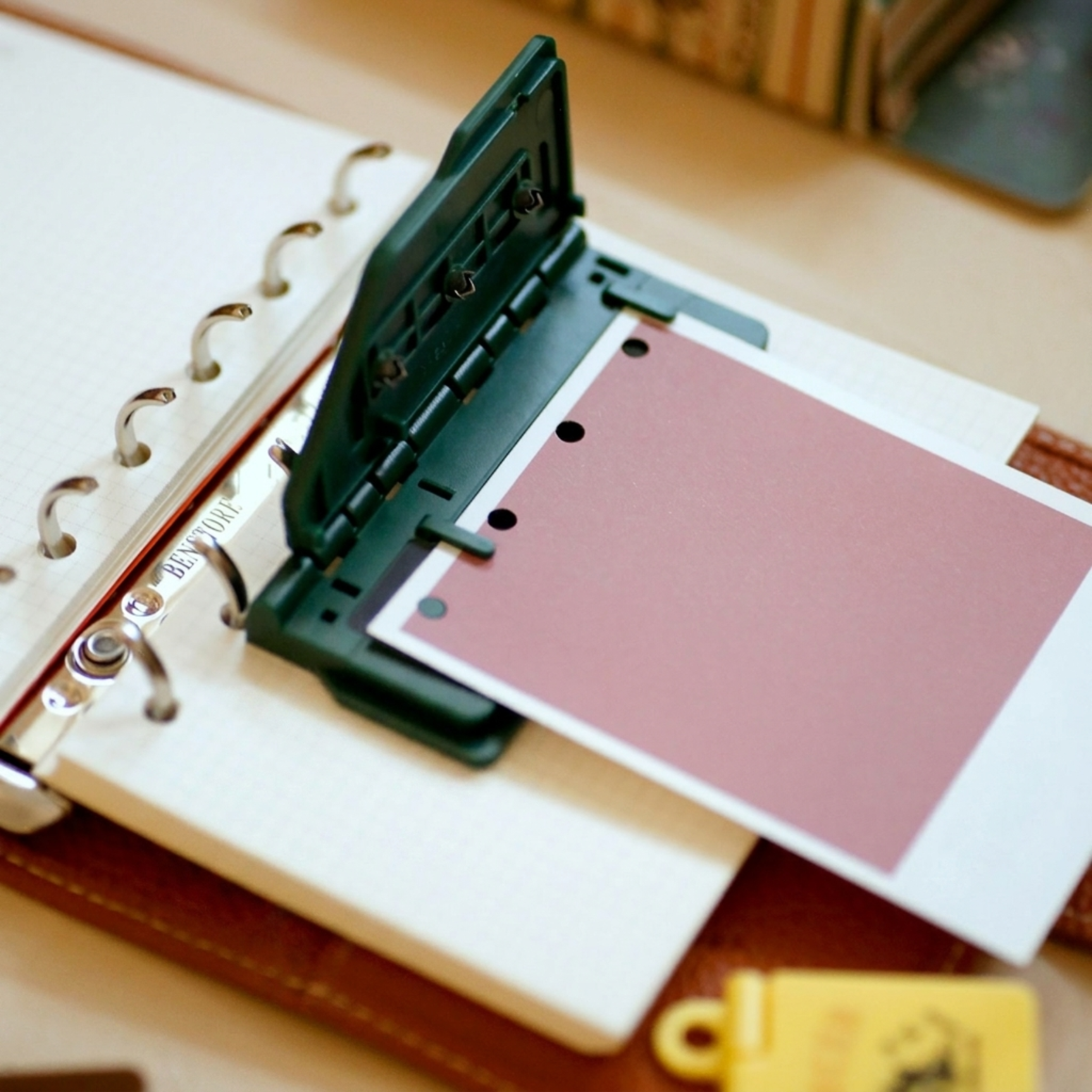 Multiple colorful mini 6-hole punches arranged on ring planner with punched paper sheets, green yellow brown pink variants.