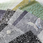 Close-up of layered fishnet, mesh, and sequin textured specialty papers in grey and green