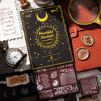 The Moonlight Starlight 29-piece vintage postal and celestial wooden stamp set in its elegant black and gold-foil box. Styled with a vintage pocket watch, magnifying glass, and wax seals for a dark academia aesthetic.