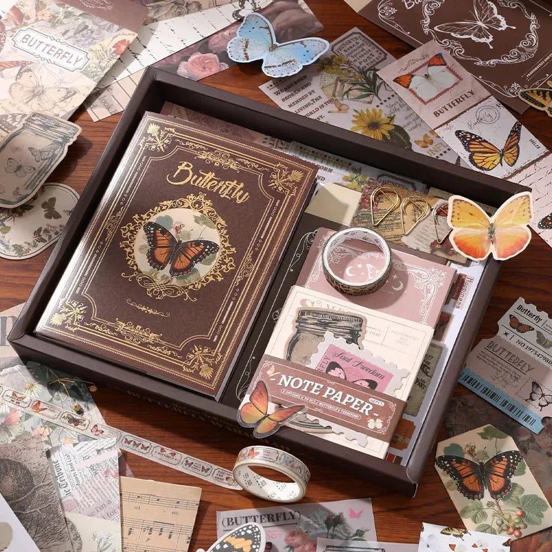 The Nature's Whispers vintage brown aesthetic journal gift box, elegantly opened on a wooden desk. Showcases the classical butterfly hardcover notebook, memo pads, gold paper clips, and washi tape, surrounded by scattered vintage ephemera