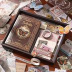 The Nature's Whispers vintage brown aesthetic journal gift box, elegantly opened on a wooden desk. Showcases the classical butterfly hardcover notebook, memo pads, gold paper clips, and washi tape, surrounded by scattered vintage ephemera