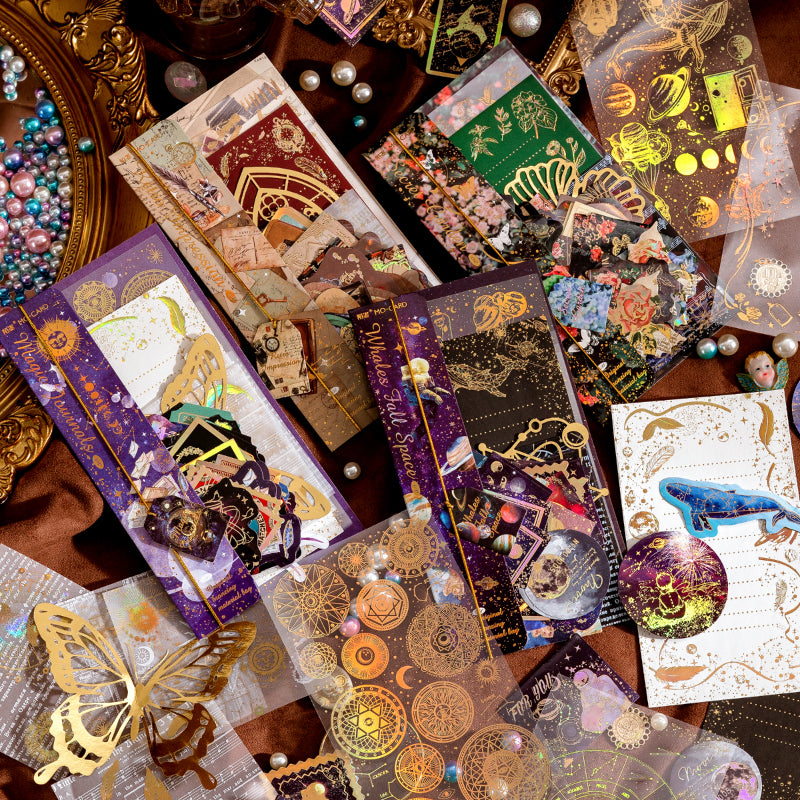 Overhead view of 4 vintage sticker packs featuring celestial whales, moths, and botanical themes with gold foil details