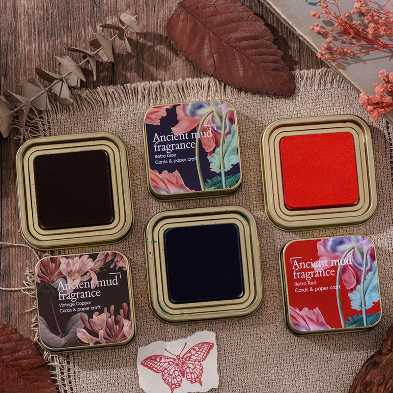 Open iron ink tins in red, blue, green and black with a stamped butterfly card