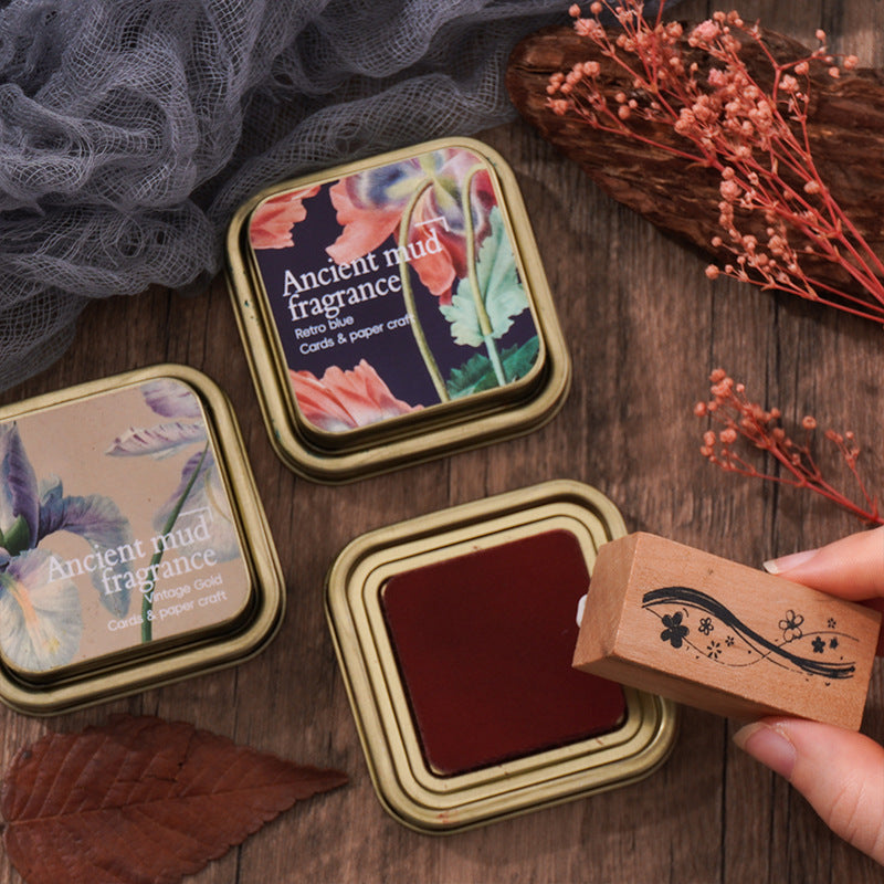 Hand lifting the lid off a Retro Red ink tin on a wooden desk