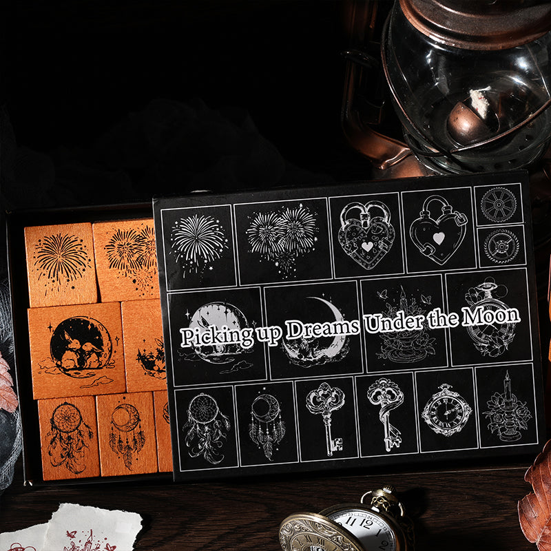 The aesthetic packaging of the Picking up Dreams Under the Moon stamp set, partially opened to reveal the wood stamps inside. Styled with an antique lantern and a vintage pocket watch.