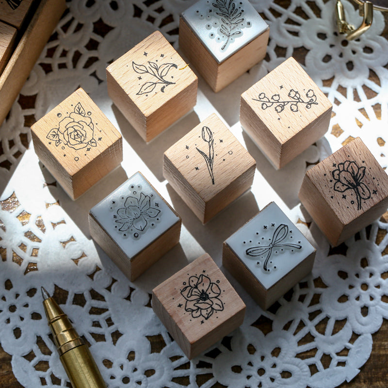 Close-up of the premium red beech wood stamps featuring delicate line-art designs of roses, tulips, and ribbons, beautifully lit by natural sunlight.