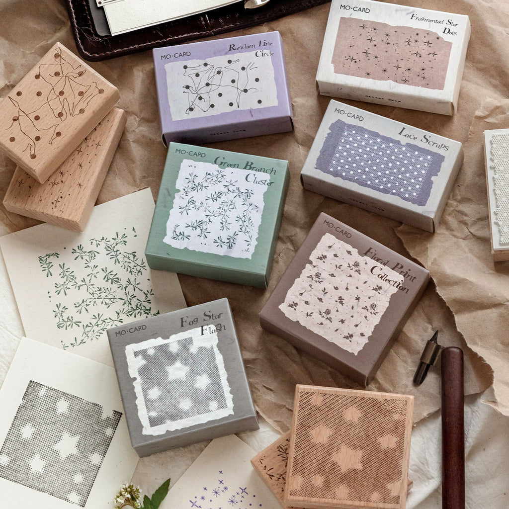 Six romantic background wooden stamps in pastel boxes with beech wood blocks, scattered on vintage kraft paper with journal and pen.