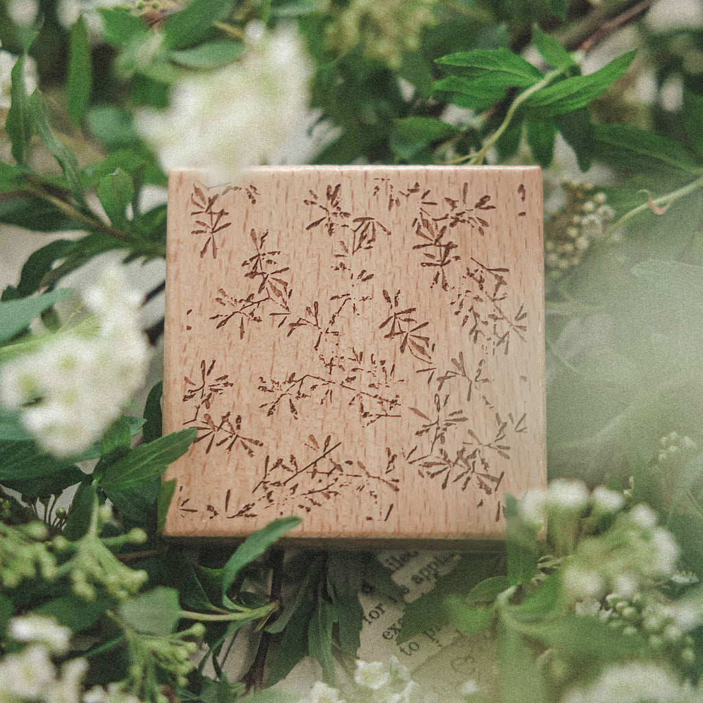 Floral print romantic background wooden stamp in fresh green foliage, soft botanical setting with natural light.