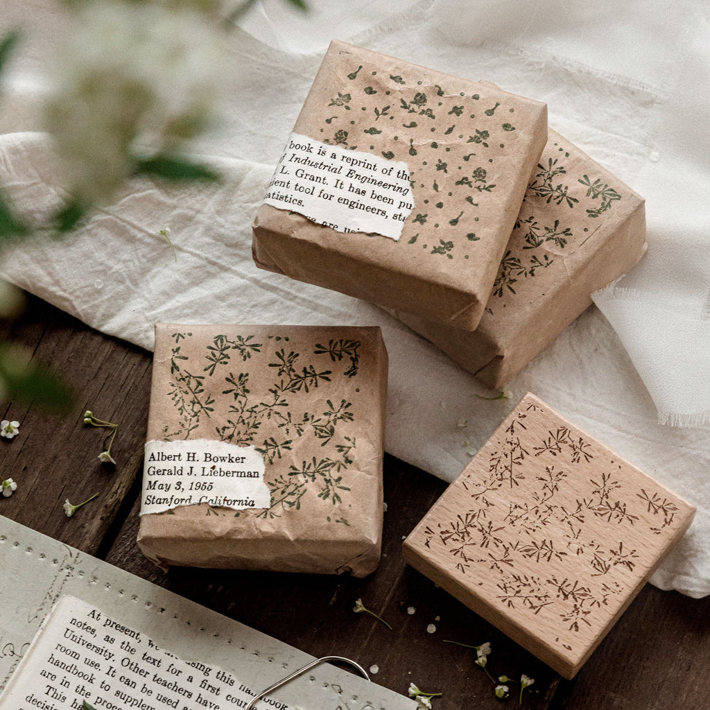 Romantic background stamps with floral impressions on brown gift wrap, vintage paper tag and twine detail.