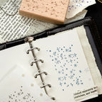Star flash romantic background stamp with blue ink impressions on ring-bound journal page, crisp celestial dots.
