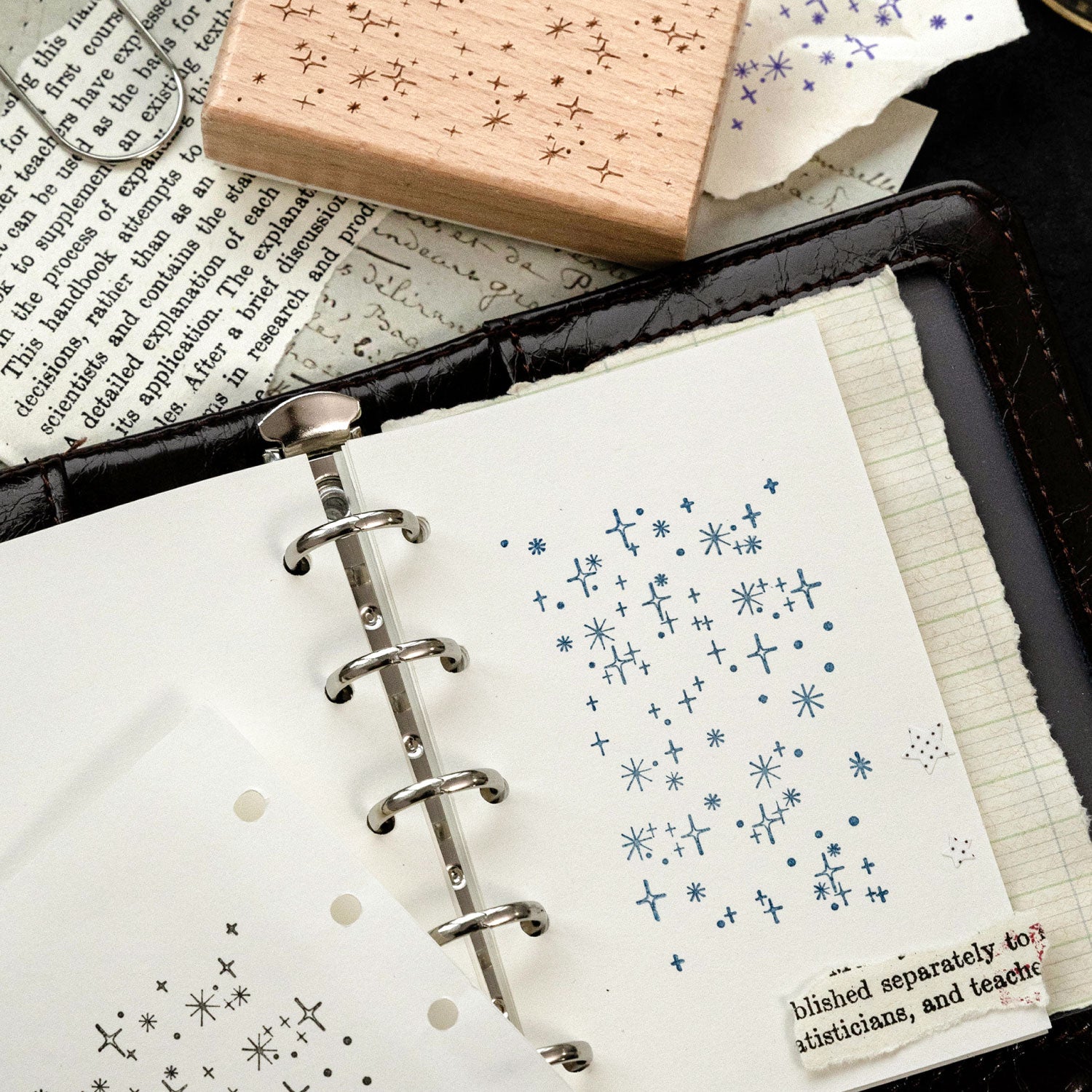 Star flash romantic background stamp with blue ink impressions on ring-bound journal page, crisp celestial dots.
