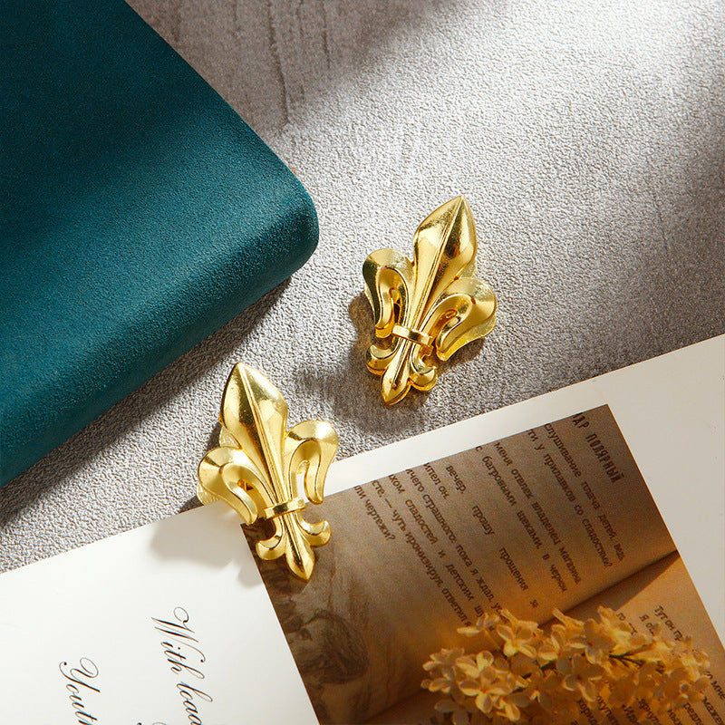 Matching set of two heavy-duty gold Fleur-de-lis metal journal clips clamping thick aged book pages. Vintage heraldic stationery.