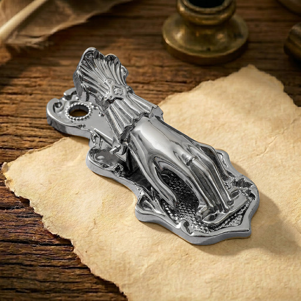 A sleek, sophisticated gunmetal black metal journal clip, shaped into a detailed Victorian Lady's Hand without a pearl. The dark, slightly metallic black finish provides a modern but antique look, clamping down old black-and-white photos and distressed paper tickets against a dark textured background.