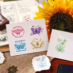 Hands stamping butterfly and diamond impressions onto white cards