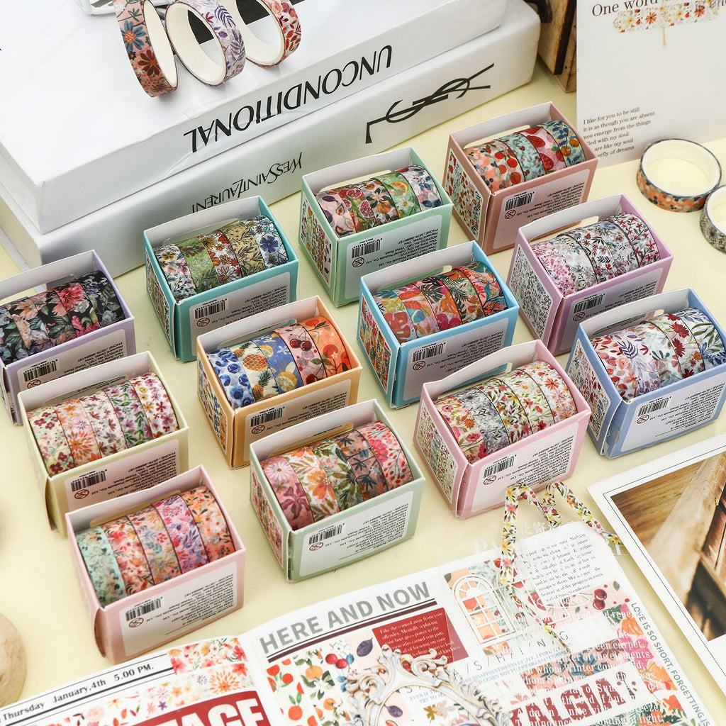 A complete collection of the 12 Summer Flowers botanical washi tape sets arranged on a desk. Each mini box contains 5 rolls of aesthetic floral and fruit masking tape for journaling.