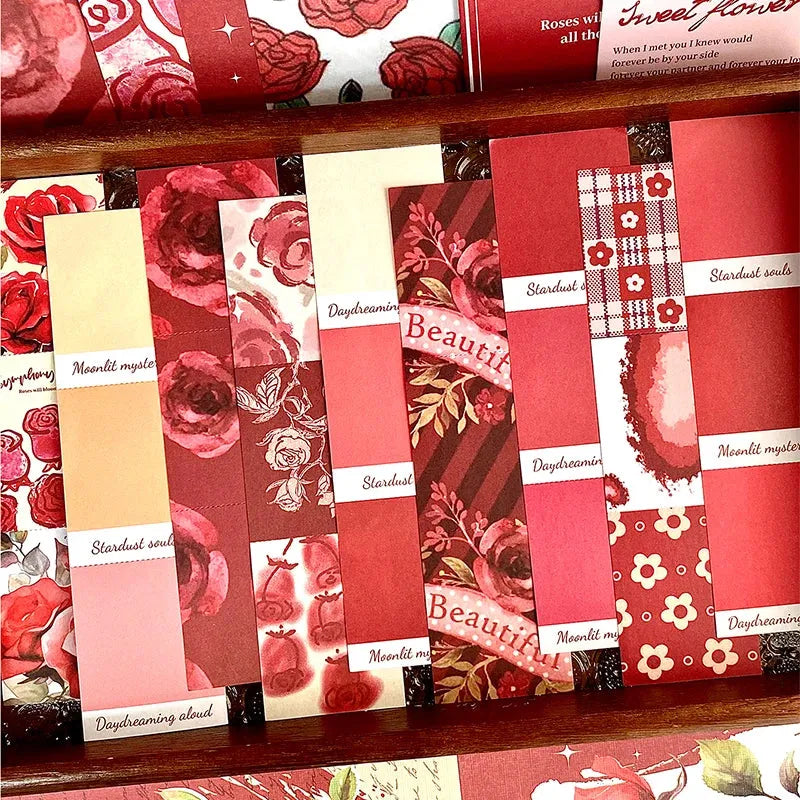 Close-up of the romantic rose-themed washi sticker strips and foldable memos from the Symphony of Rose journal kit, showing vibrant red floral patterns and vintage typography.
