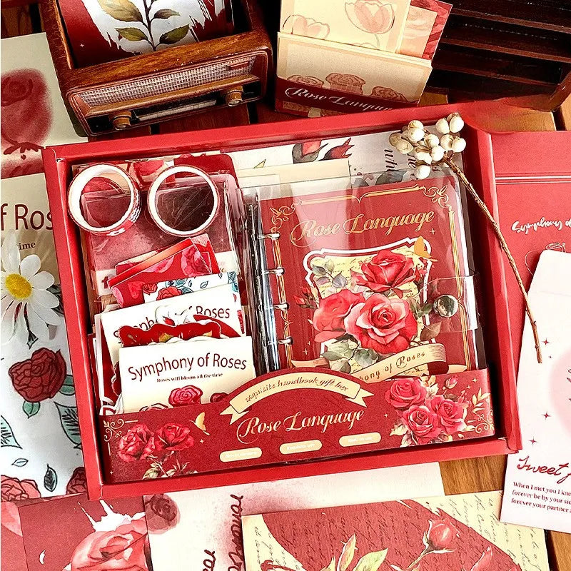An open Symphony of Rose romantic red aesthetic journal gift box on a wooden desk, revealing the red A6 binder notebook with a floral cover, matching washi tapes, memo papers, and sticker packs, perfect for gifting and creative planning.
