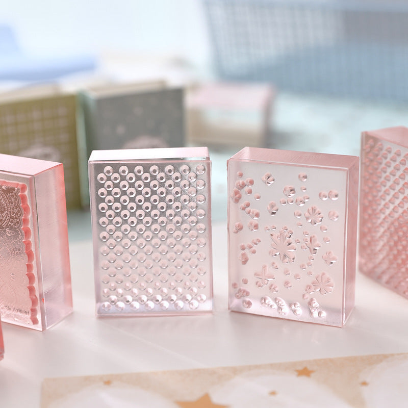 Textured acrylic stamps standing in a row – carved lace and gingham patterns on clear acrylic blocks