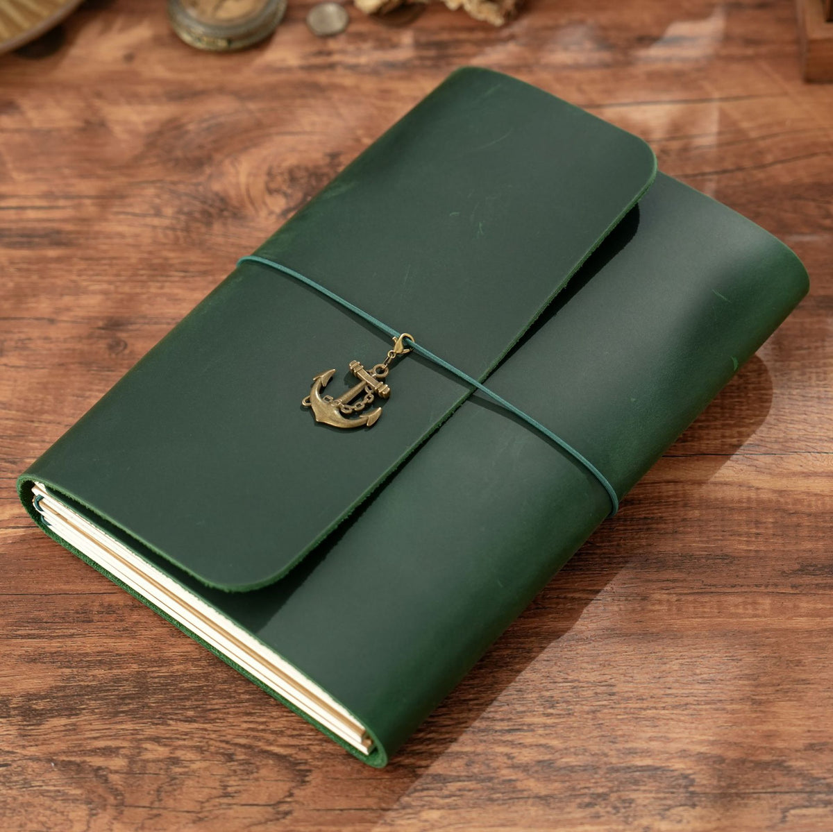 Dark green A5 trifold leather journal lying flat on rustic wood