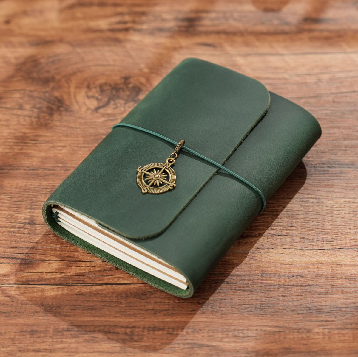 Dark green trifold leather journal lying flat on rustic wood