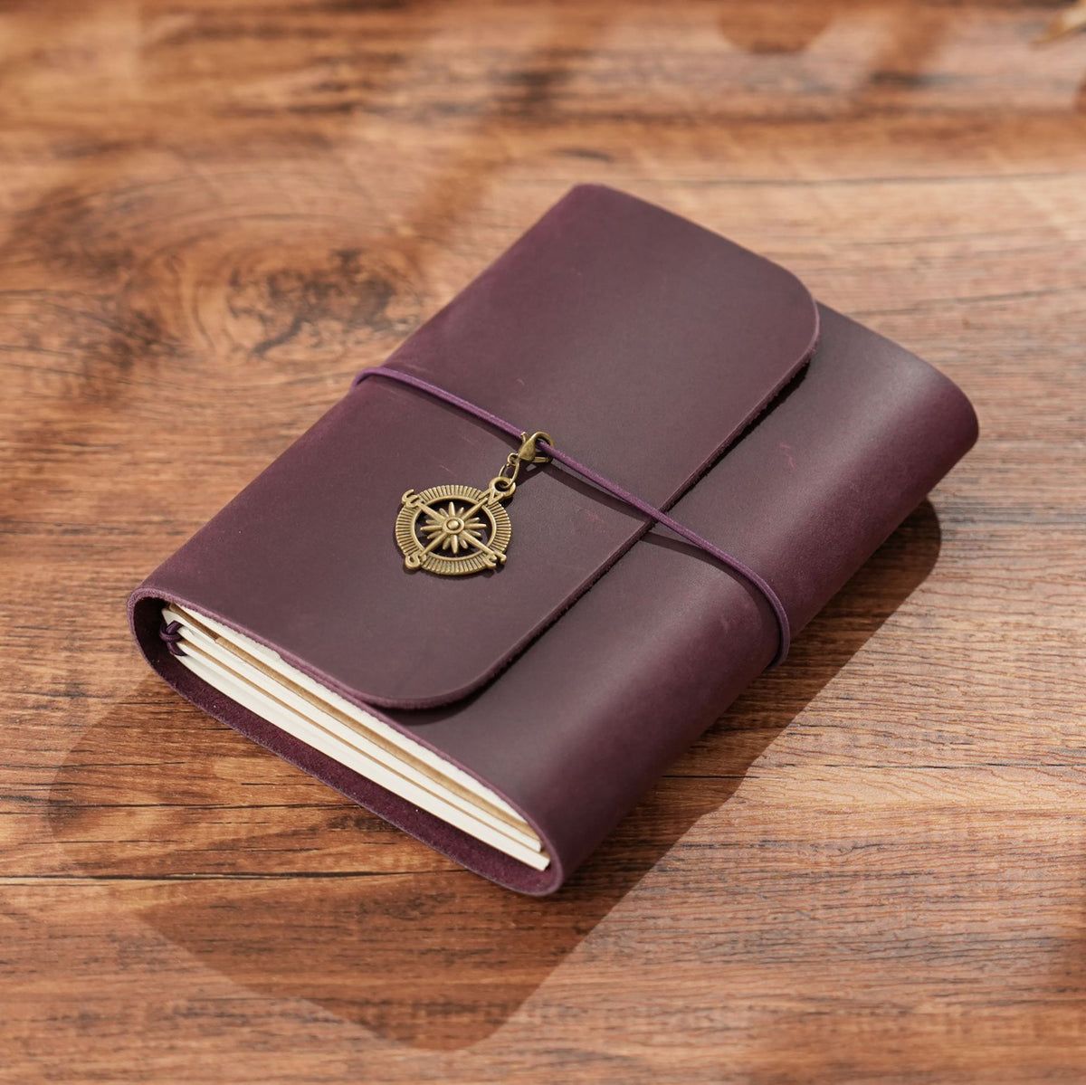 Dark purple trifold leather notebook with cord wrap and compass charm
