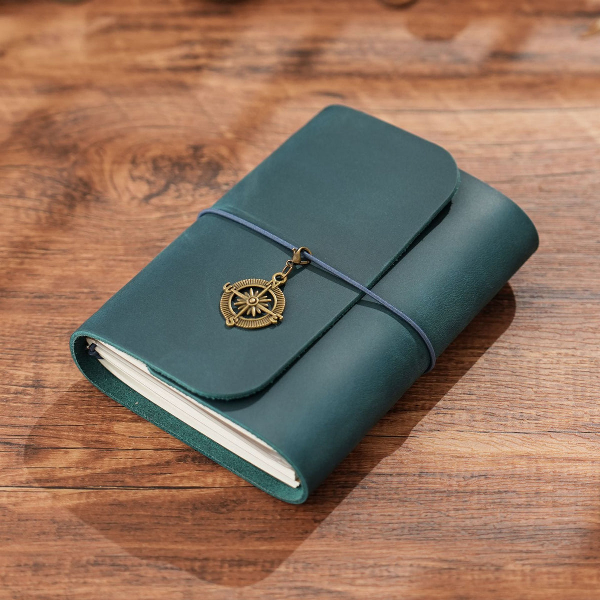 Vintage blue trifold leather journal with brass charm on wood