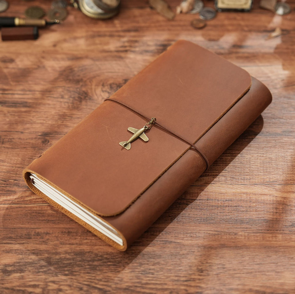 Brown trifold leather journal with elastic cord and brass cross charm