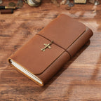 Brown trifold leather journal with elastic cord and brass cross charm