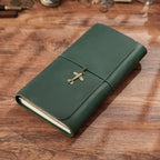 Dark green trifold leather journal lying flat on weathered wood