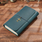 Vintage blue trifold leather journal with cord wrap closure on wood