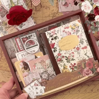 High-quality shot of the open Letter From Flowers gift box showcasing the complete floral journaling kit contents. Includes text overlay 'UNBOX INSPIRATION' and displays the notebook, washi tape, PET stickers, and ephemera for vintage scrapbooking.