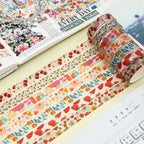 A close-up of unrolled Summer Flowers washi tape strips revealing detailed botanical, cherry, and strawberry patterns, laid out beautifully next to a decorated bullet journal.