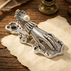 A detailed view of a vintage antique silver Victorian Lady's Hand metal journal clip clamping a piece of ticket-style aged paper. Soft bokeh background.
