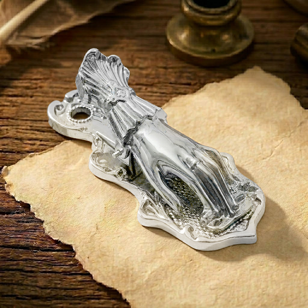 A detailed vintage antique silver metal journal clip, shaped like a Victorian Lady's Hand without a pearl. The silver has a sophisticated, slightly aged patina. It is holding down a rolled section of textured, aged paper with French script. Perfect for adding a classic touch to junk journaling.